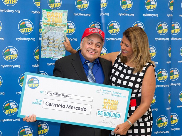 Carmelo Mercado posa com cheque simbólico de US$ 5 milhões, após ganhar na loteria em Nova York (Foto: Philip Kamrass/New York State Gaming Commission via AP) sept-11-lottery-winne fran