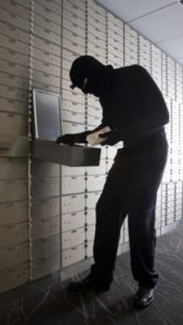 Masked thief in bank vault going through safety deposit box