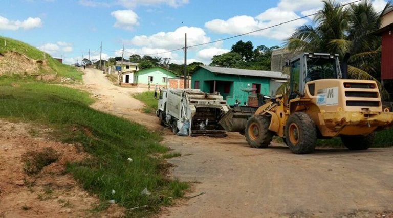 Caminhão de lixo fica atolado na pista e é resgatado por trator