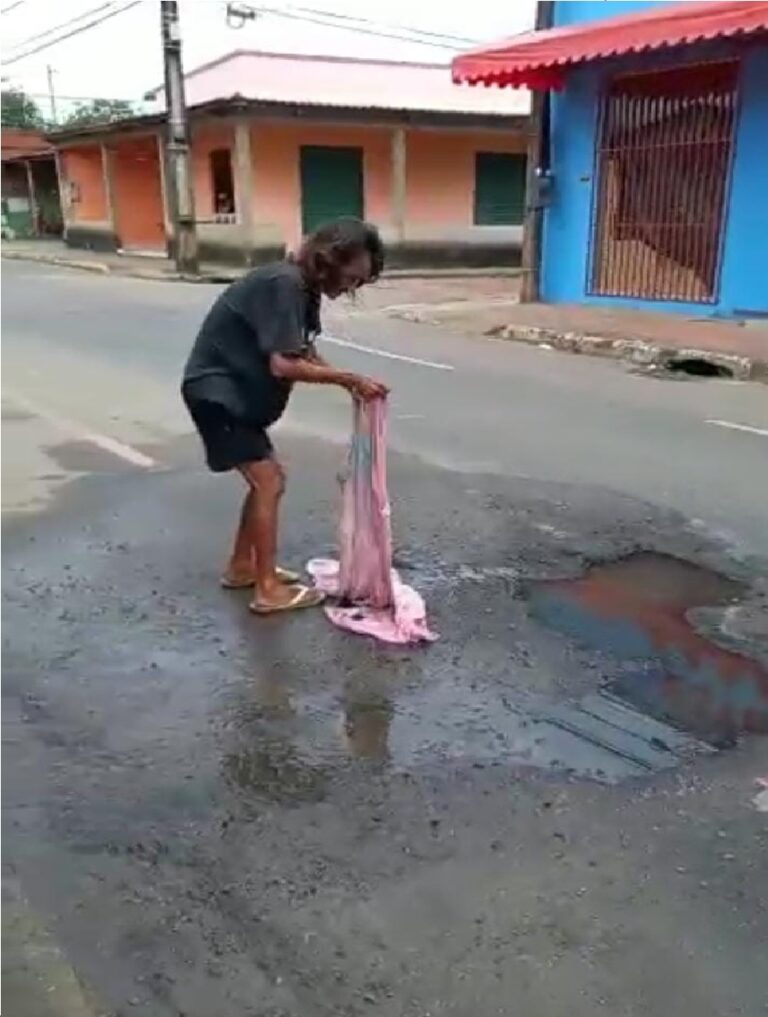 No meio da rua, mulher lava lençol com água acumulada em buraco no AC; veja vídeo