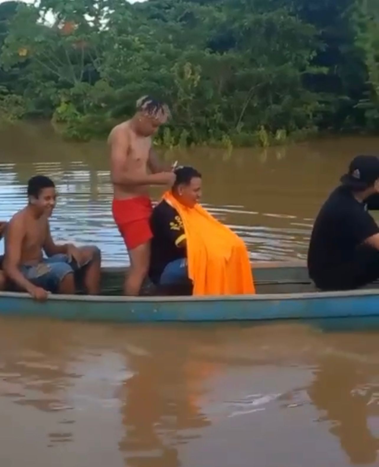 VÍDEO: barbeiro viraliza ao cortar cabelo em canoa durante alagação no Acre