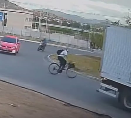 Ciclista ‘voa’ após tentar ultrapassar caminhão e colidir com moto em rotatória
