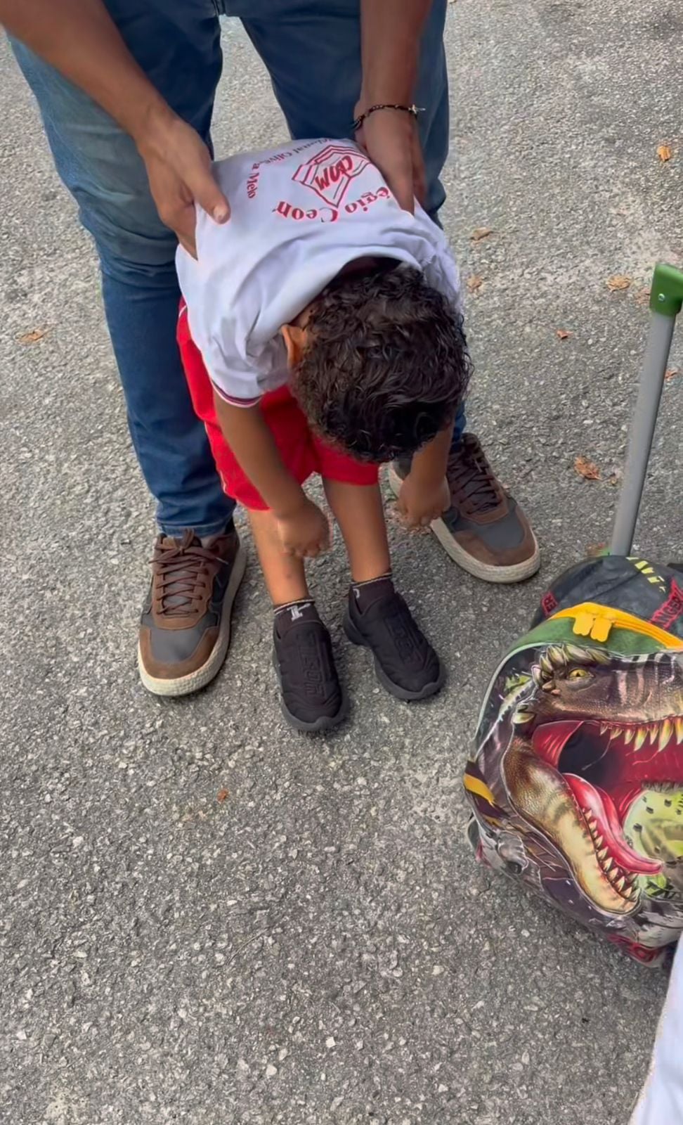 Vídeo mostra menino fingindo dormir para evitar aula; pai tenta colocá-lo no chão, mas criança amolece o corpo e cena divertida viraliza nas redes sociais.