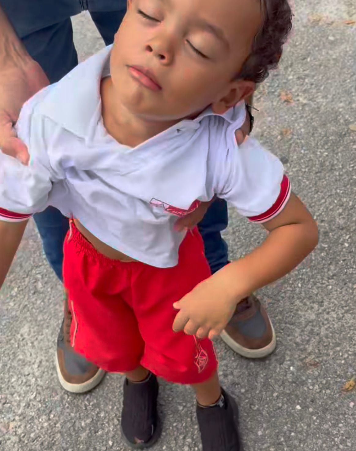 Vídeo mostra menino fingindo dormir para evitar aula; pai tenta colocá-lo no chão, mas criança amolece o corpo e cena divertida viraliza nas redes sociais.