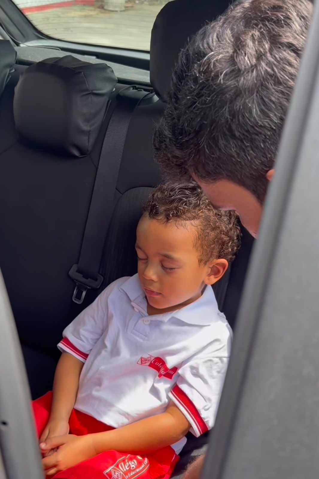 Vídeo mostra menino fingindo dormir para evitar aula; pai tenta colocá-lo no chão, mas criança amolece o corpo e cena divertida viraliza nas redes sociais.