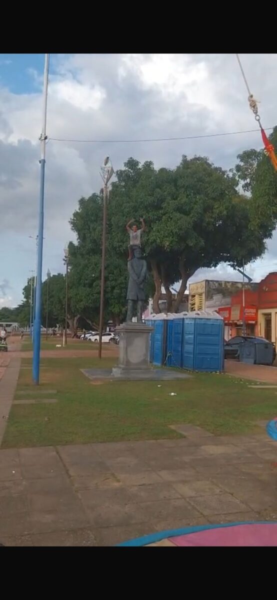 Homem sobe em estátua e acena para pedestres na Gameleira