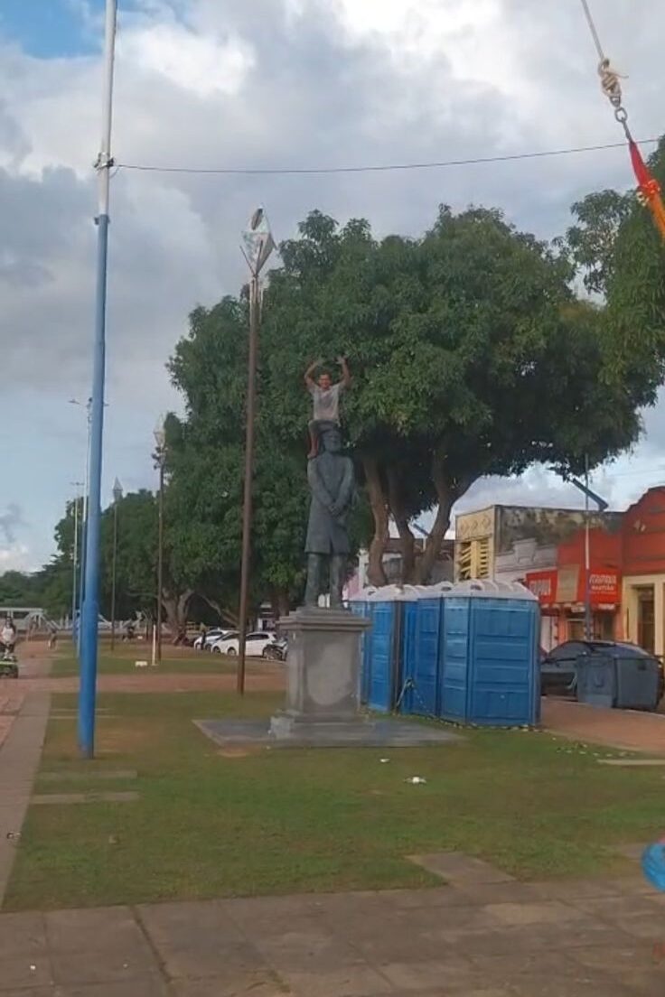 Homem sobe em estátua e acena para pedestres na Gameleira