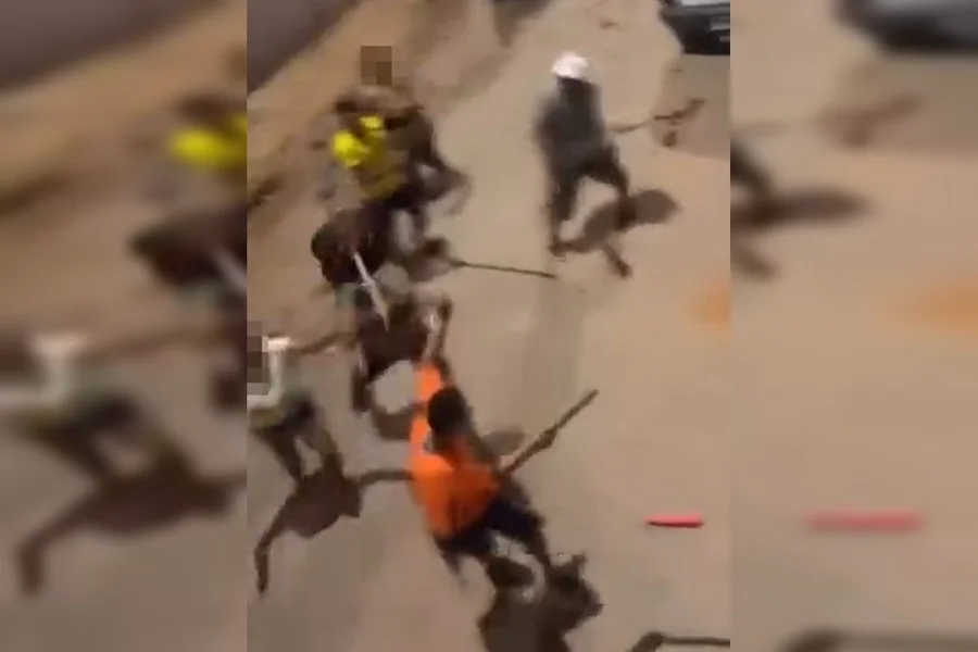 Imagens gravadas por moradores e que circulam nas redes sociais mostram o momento em que um jovem é cercado e agredido violentamente por um grupo de pelo menos quatro homens. A brutalidade incluiu o uso de pedaços de madeira e até uma churrasqueira como armas, além de diversos golpes de faca.