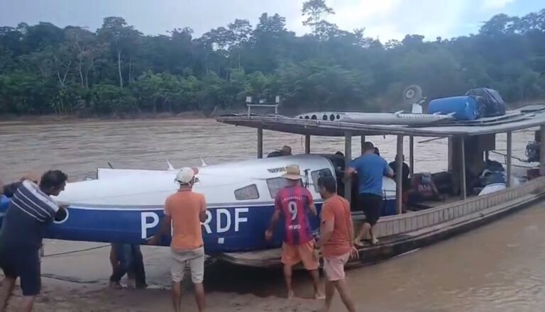 Partes de avião são colocadas em embarcação após acidente no Rio Tarauacá